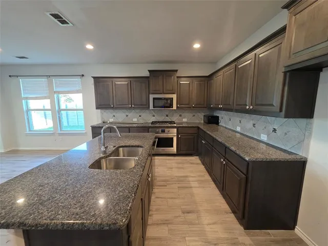 a kitchen with stainless steel appliances granite countertop a sink stove microwave and refrigerator