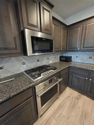 a kitchen with granite countertop wooden cabinets and stainless steel appliances