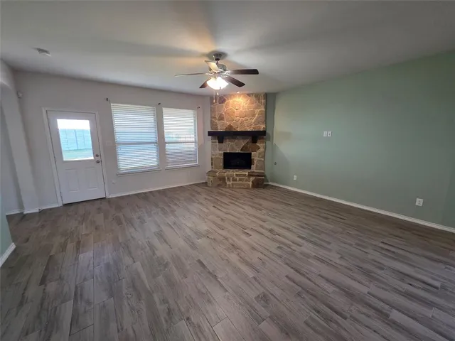 an empty room with wooden floor chandelier fan and windows