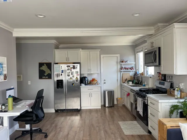 a kitchen with stainless steel appliances granite countertop a refrigerator a stove top oven a sink dishwasher and white cabinets with wooden floor