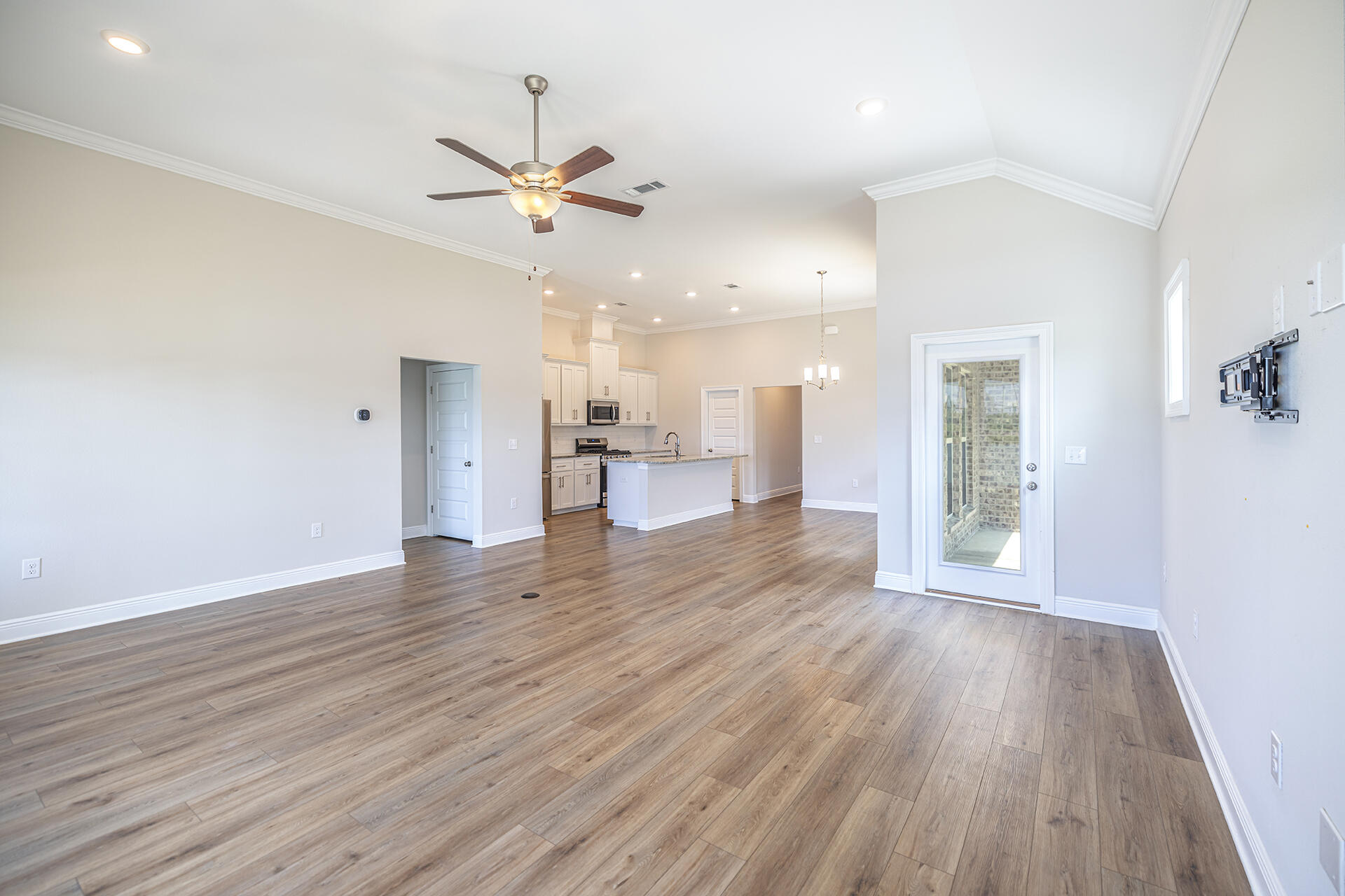 8959 Eureka Street Milton, FL 32583 - Photo 21 of 37 a view of a big room with wooden floor a ceiling fan and kitchen space