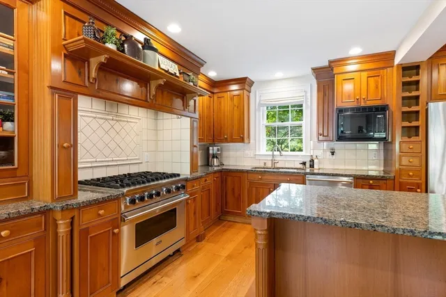 a kitchen with stainless steel appliances granite countertop a stove a sink and a microwave