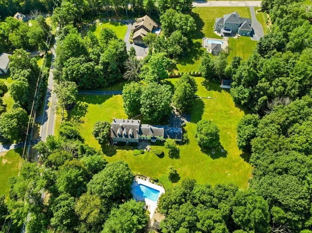 an aerial view of a residential houses with outdoor space and trees all around