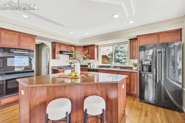 13884 Windy Oaks Road Colorado Springs, CO 80921 - Photo 7 of 21 Kitchen with a center island, refrigerator with ice dispenser, stainless steel gas stovetop, dobule oven black, and a sink