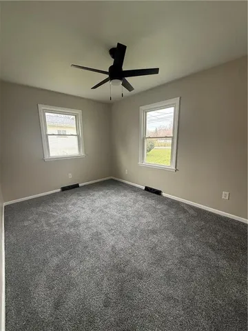 an empty room with windows and fan view