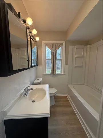 a bathroom with a sink a toilet a mirror and bathtub