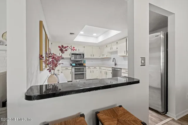 a kitchen with stainless steel appliances granite countertop a sink and a refrigerator