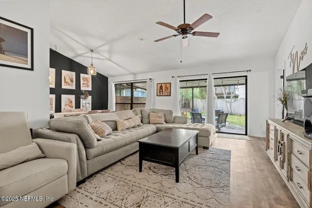 a living room with furniture a ceiling fan and a flat screen tv