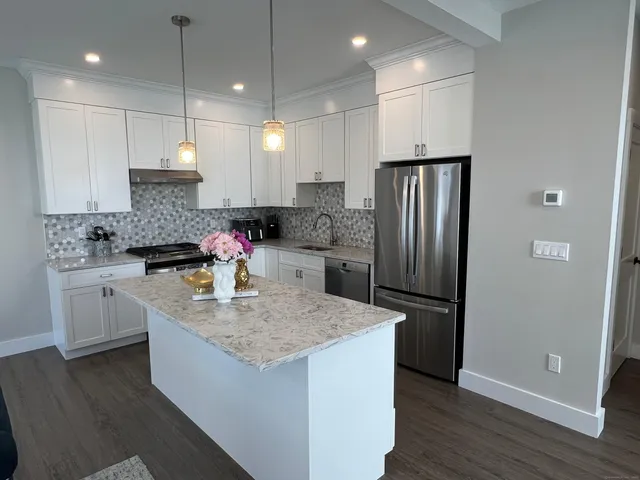 a kitchen with stainless steel appliances granite countertop a sink refrigerator and cabinets