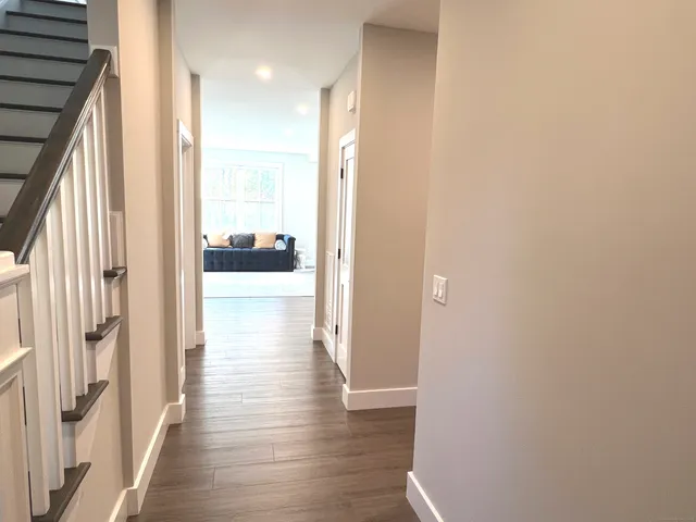 a view of a hallway with wooden floor and a bathroom with a sink