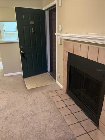a view of an empty room with wooden floor and a fireplace