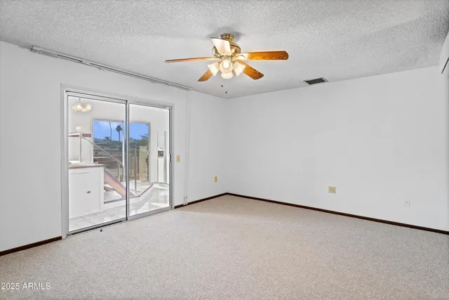 an empty room with chandelier fan and glass door