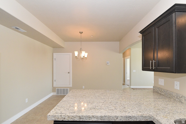 241 West Ridge Road Saratoga Springs, UT 84045 - Photo 10 of 21 Kitchen countertop featuring a light-toned speckled surface, dark wood-finish cabinetry, and a contemporary chandelier