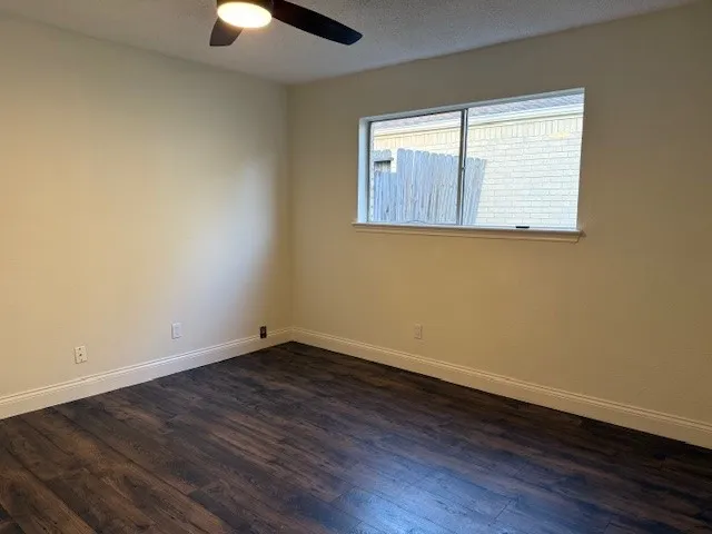 an empty room with wooden floor chandelier fan and windows