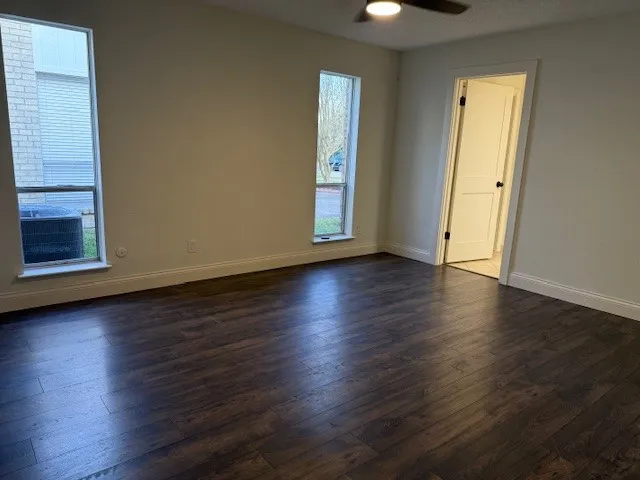 an empty room with wooden floor and windows