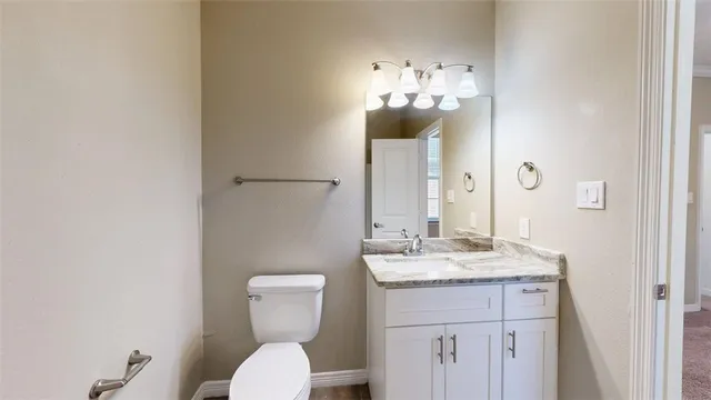 a bathroom with a granite countertop sink vanity mirror and toilet
