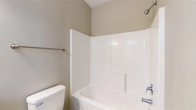 a bathroom with a white bath tub and toilet