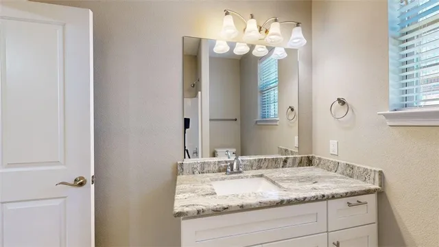 a bathroom with a granite countertop sink and a mirror