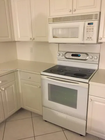 a kitchen with white cabinets and appliances