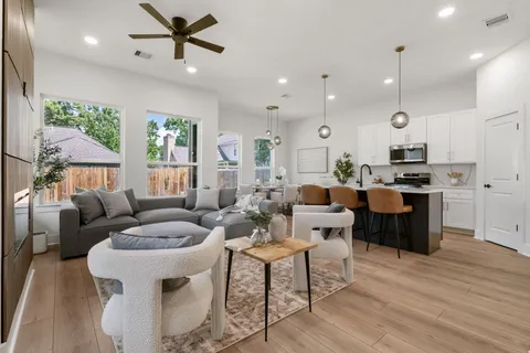 a living room with furniture kitchen area and a wooden floor