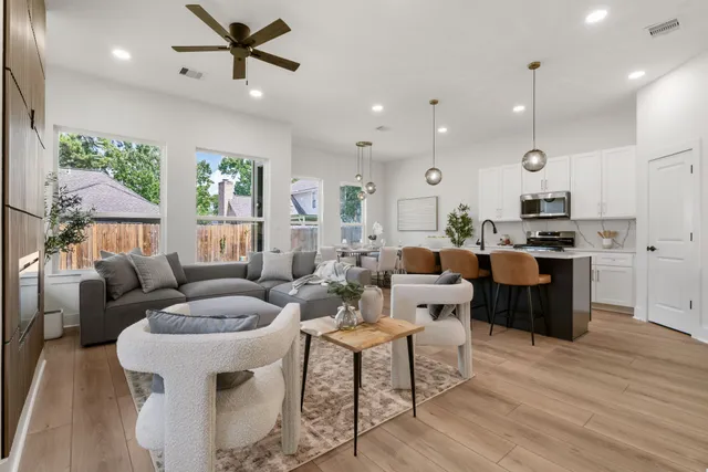a living room with furniture kitchen area and a wooden floor
