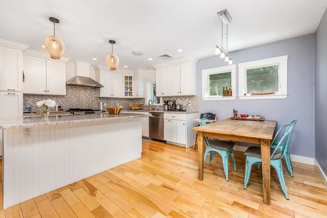 a kitchen with stainless steel appliances kitchen island granite countertop a sink a stove a dining table and chairs