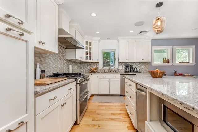 a kitchen with stainless steel appliances granite countertop sink stove and white cabinets