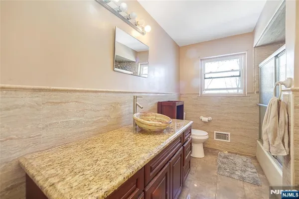a bathroom with a granite countertop sink and a toilet
