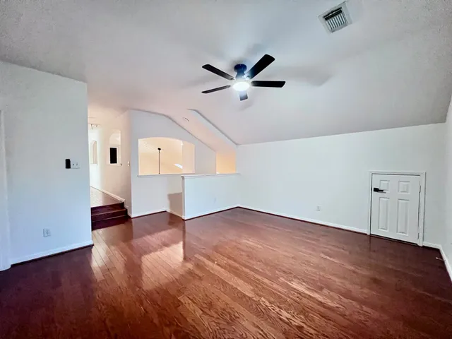 an empty room with wooden floor fan and windows