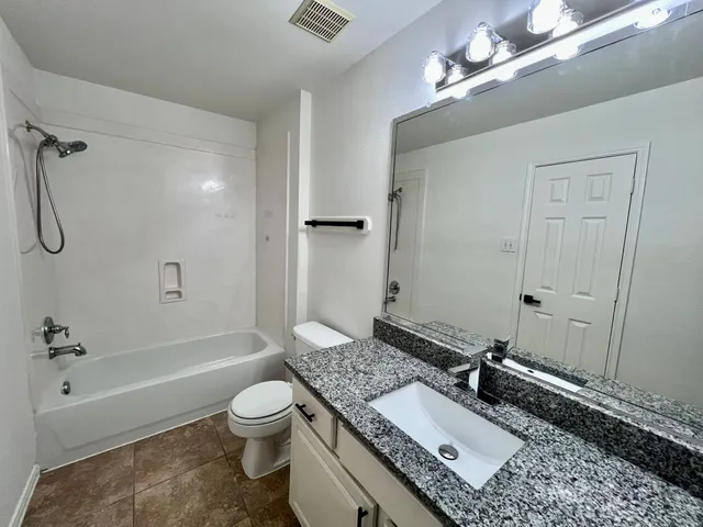 a bathroom with a granite countertop sink a toilet and shower
