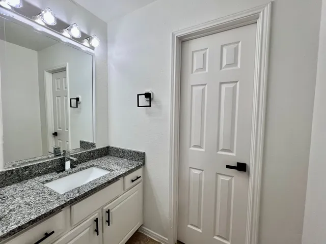 a bathroom with a granite countertop sink and a mirror