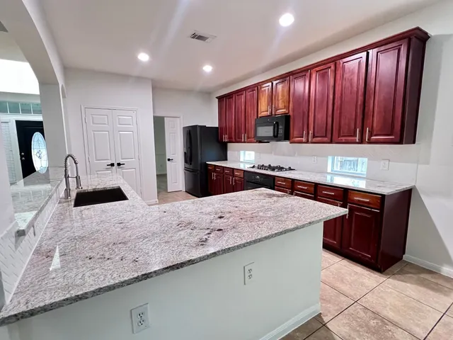 a kitchen with kitchen island granite countertop wooden cabinets a refrigerator and granite counter tops