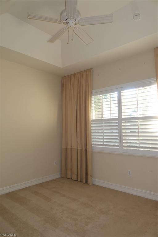 7168 Lemuria Circle, Unit 1701 Naples, FL 34109 - Photo 31 of 39 Room featuring a tray ceiling with a ceiling fan, plush carpeting, and plantation shutters