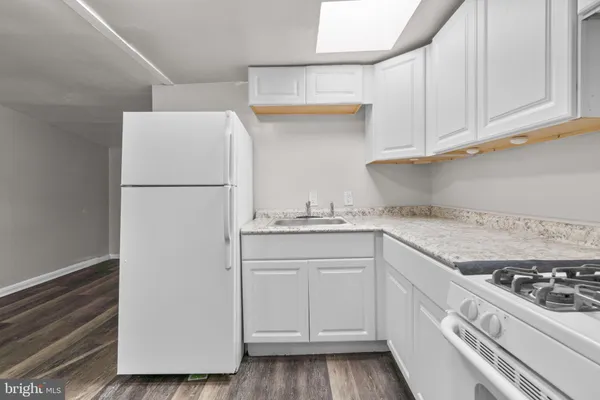 a kitchen with granite countertop white cabinets and white appliances