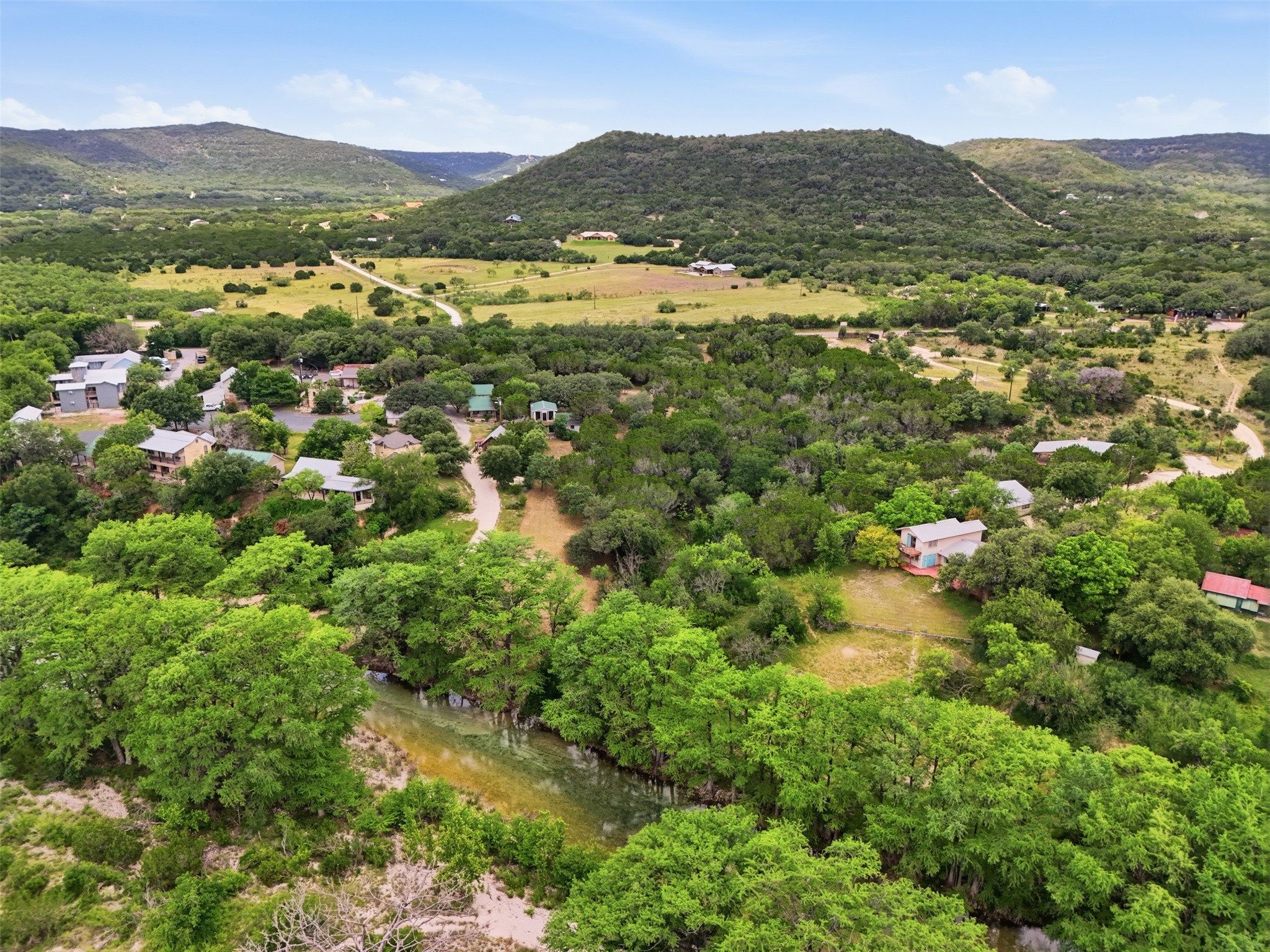 1260 Magers Road Concan, TX 78838 - Photo 12 of 40 A river meanders through a community nestled within a verdant, hilly landscape.