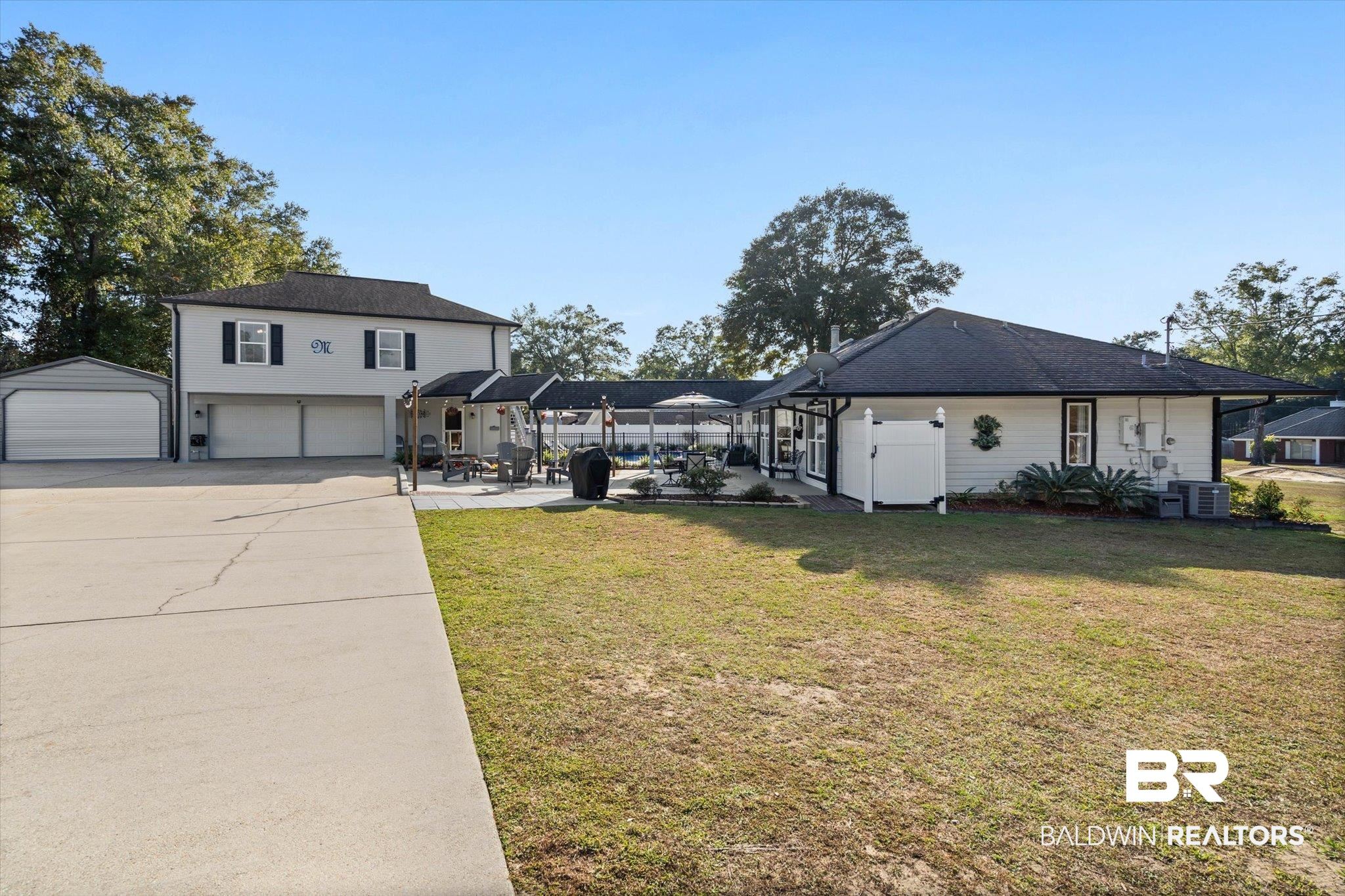 4567 Pine Avenue Saraland, AL 36571 - Photo 21 of 48 View of green lawn featuring a garage, glass enclosure, concrete driveway, and a patio area