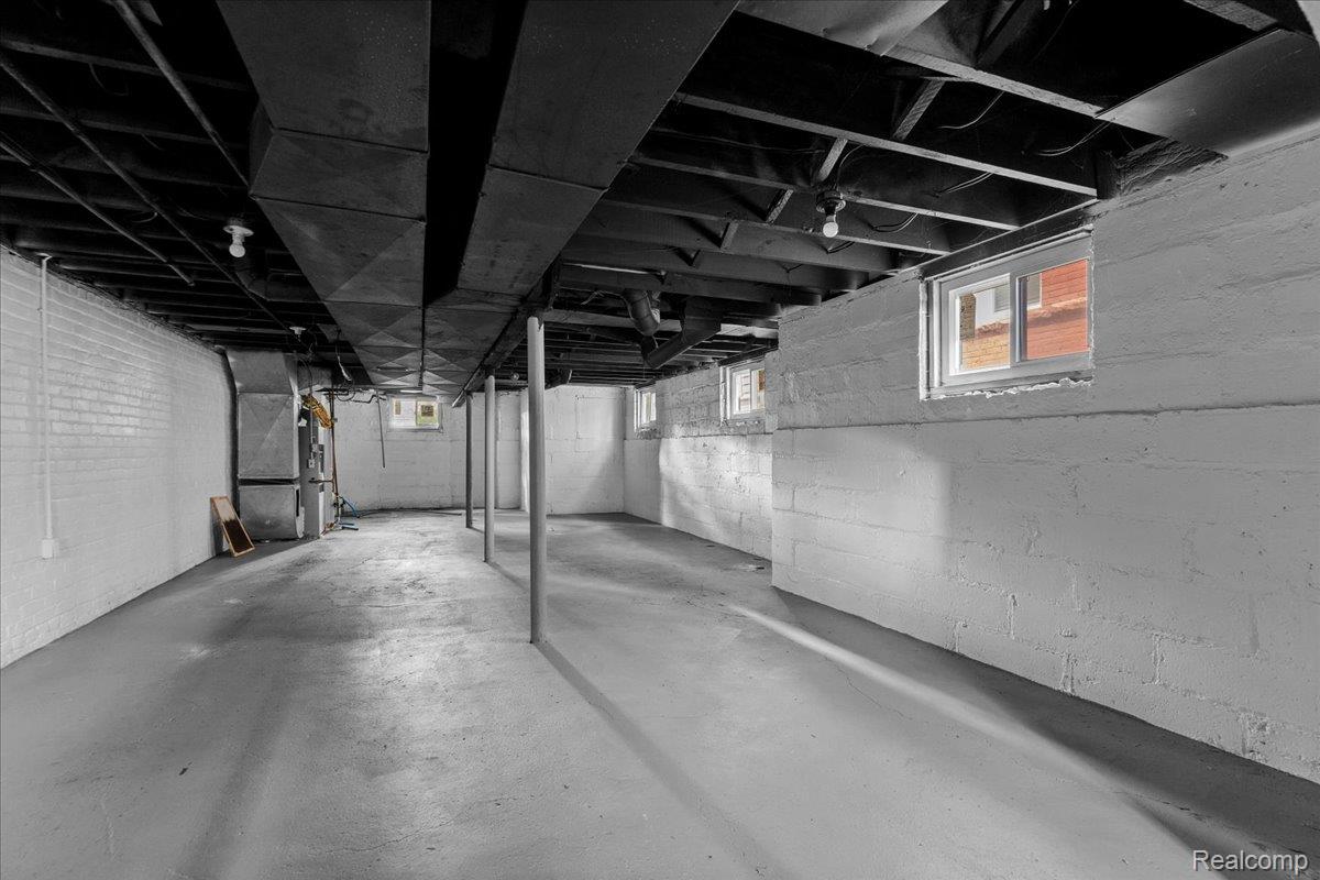 58 East Philadelphia Street Detroit, MI 48202 - Photo 21 of 24 Spacious unfinished basement featuring white painted brick walls, exposed ceiling joists, concrete flooring, and multiple windows