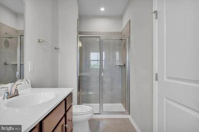 a bathroom with a shower sink vanity mirror and toilet