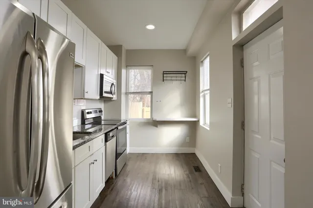 a kitchen with stainless steel appliances a refrigerator and wooden floor