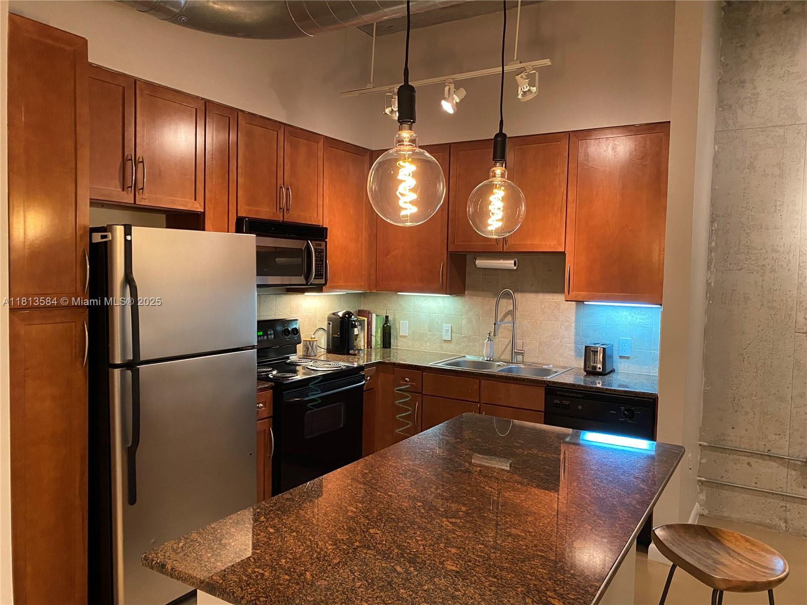 2001 Biscayne Boulevard, Unit 3203 Miami, FL 33137 - Photo 8 of 15 a kitchen with granite countertop a refrigerator a stove a kitchen island a dining table and chairs