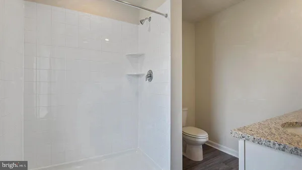 a bathroom with a granite countertop toilet and a sink