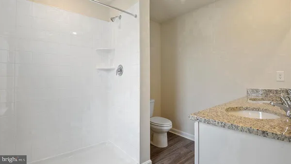 a bathroom with a granite countertop sink toilet and shower