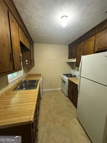 a kitchen with a sink a stove top oven and refrigerator