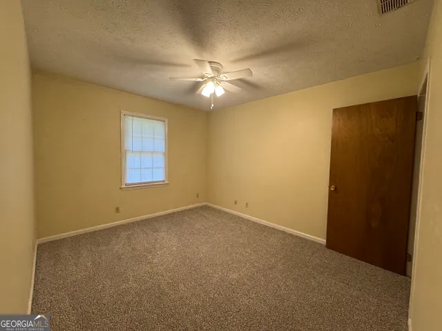 an empty room with a ceiling fan and a window