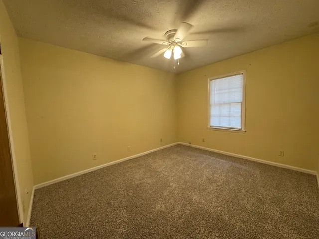 an empty room with a chandelier fan and windows
