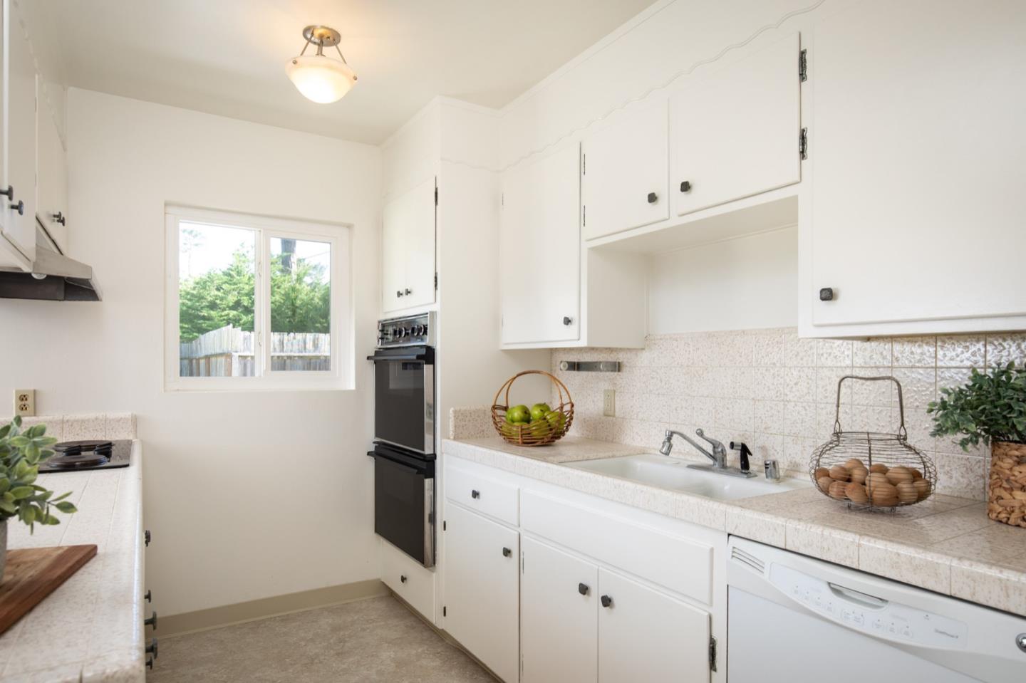 1043 Ocean Road Pebble Beach, CA 93953 - Photo 6 of 18 a kitchen with stainless steel appliances white cabinets and a window