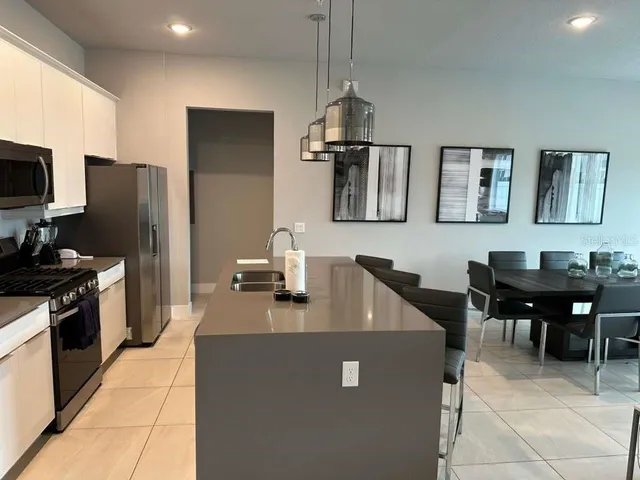 a kitchen with stainless steel appliances granite countertop a refrigerator a stove a sink a dining table and chairs