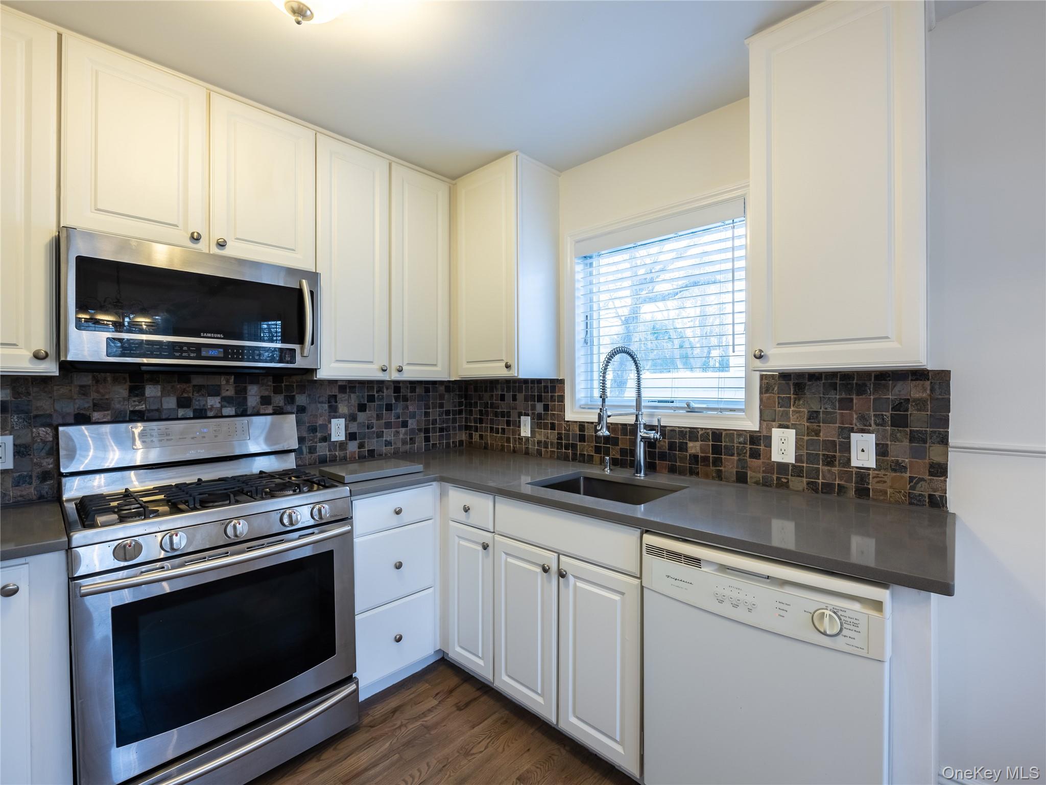21 Marwood Road North Port Washington, NY 11050 - Photo 29 of 35 a kitchen with stainless steel appliances granite countertop a sink a stove a microwave and wooden cabinets