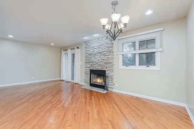a view of a livingroom with a fireplace wooden floor and chandelier