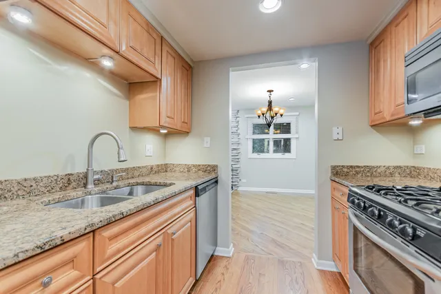 a kitchen with stainless steel appliances granite countertop a sink stove and cabinets